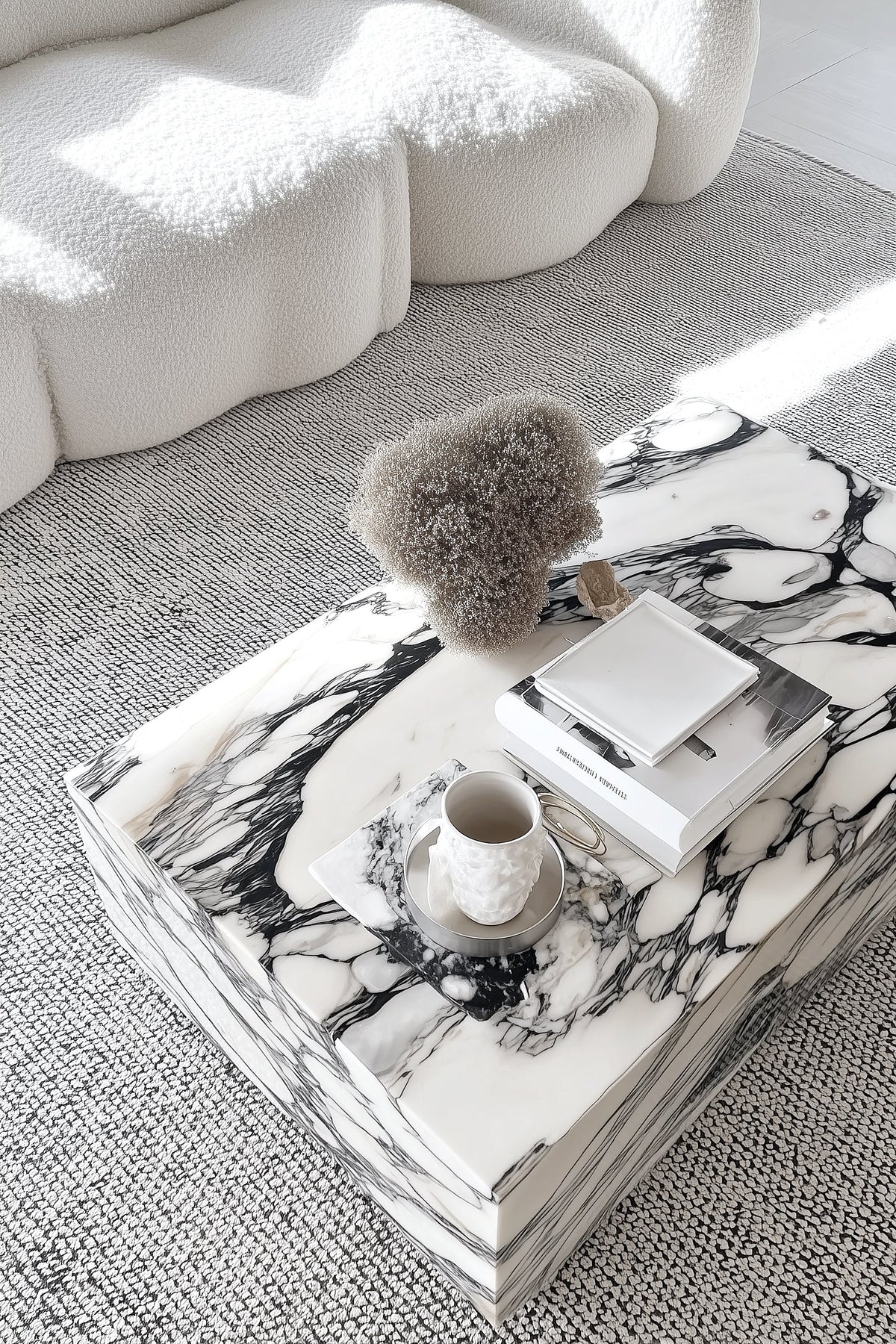 Marble cube coffee table on a grey rug beside a curved white sofa