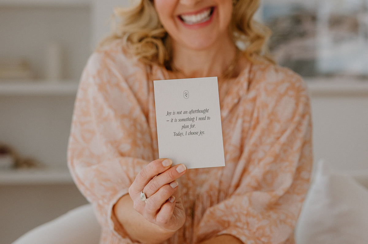 Person in a pink knit holding an affirmation card