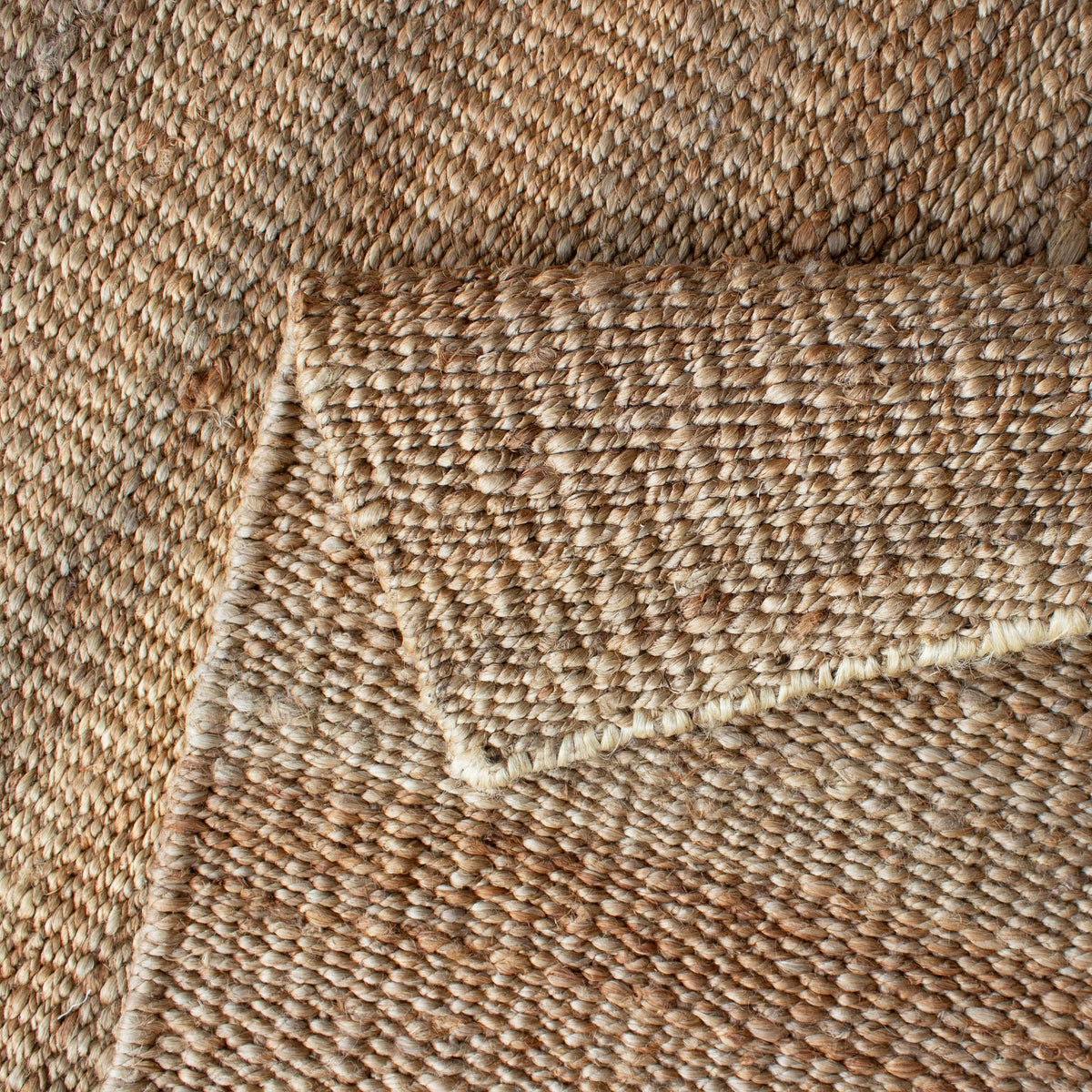 Folded corner of the jute rug showing the reverse of the weave