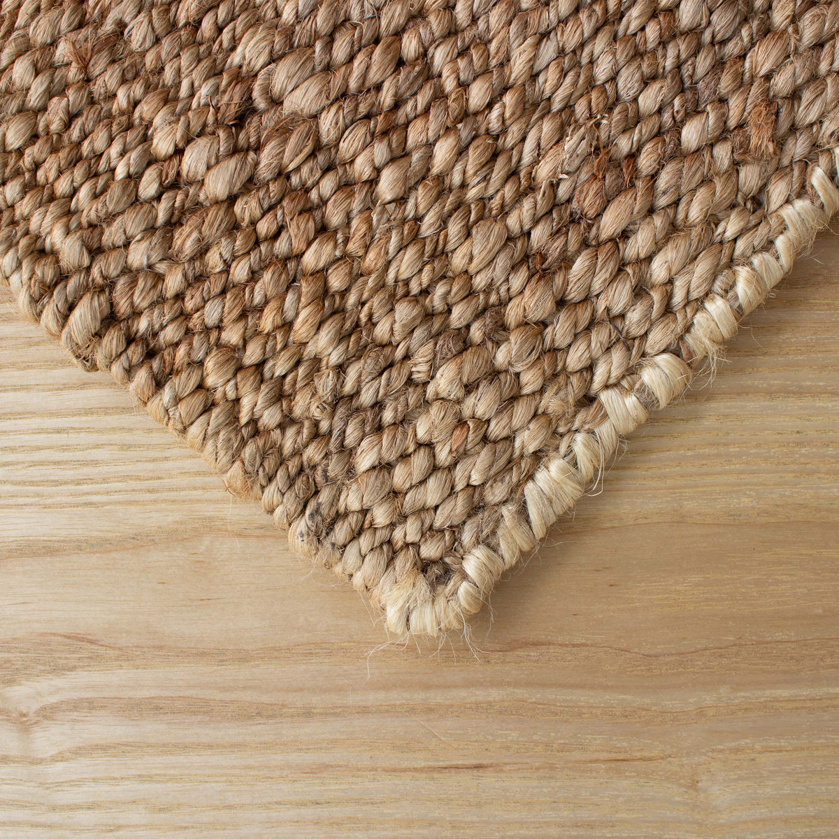 Corner of the jute rug showing its bound edge on a pale timber floor