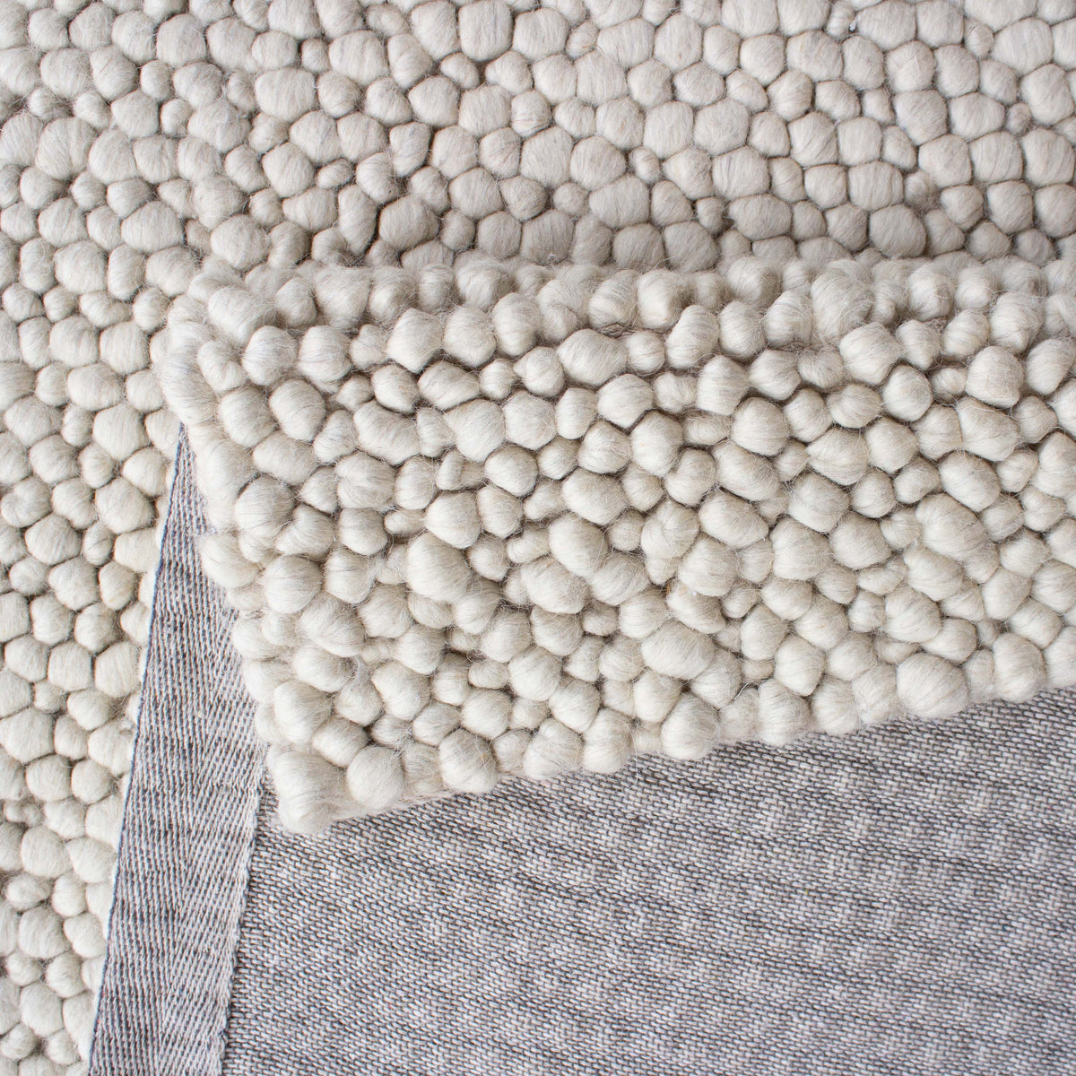 Folded edge revealing the grey backing beneath the beige loops