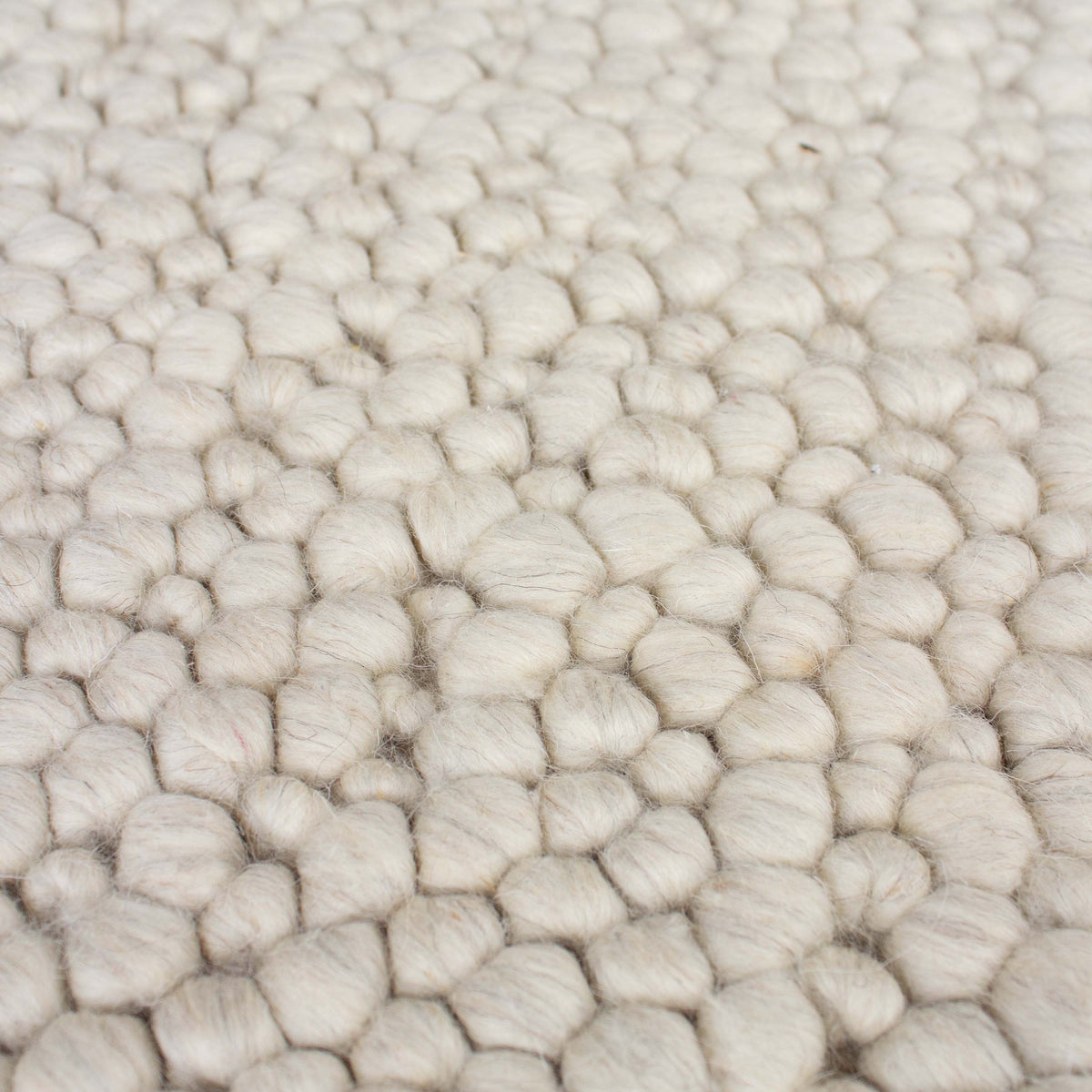 Close view of the rounded beige wool loops, like smooth river stones