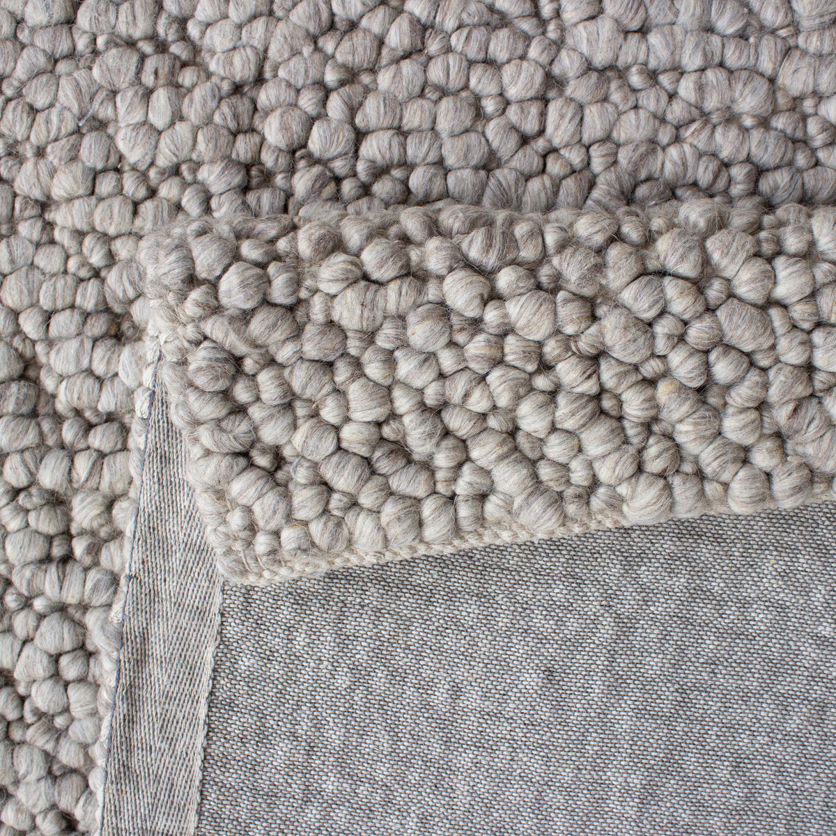 Folded corner showing the grey backing under the chunky loop pile