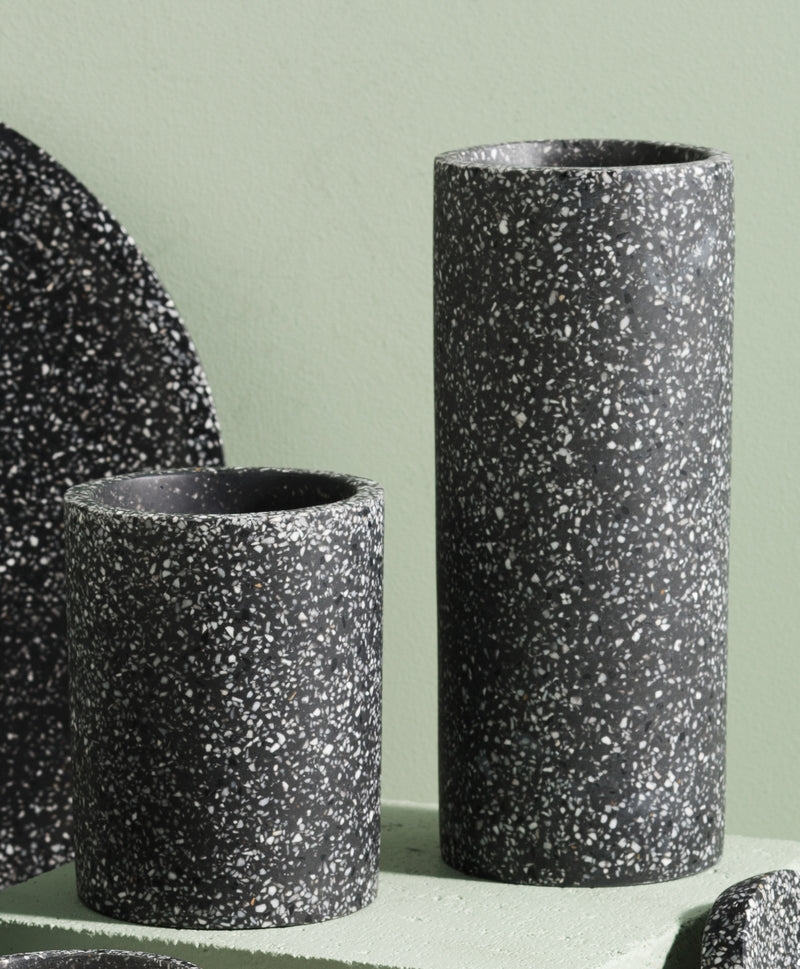 A set of Zakkia black Terrazzo Vessels on a green background, perfect for terrazzo vessel enthusiasts looking for stylish storage options.