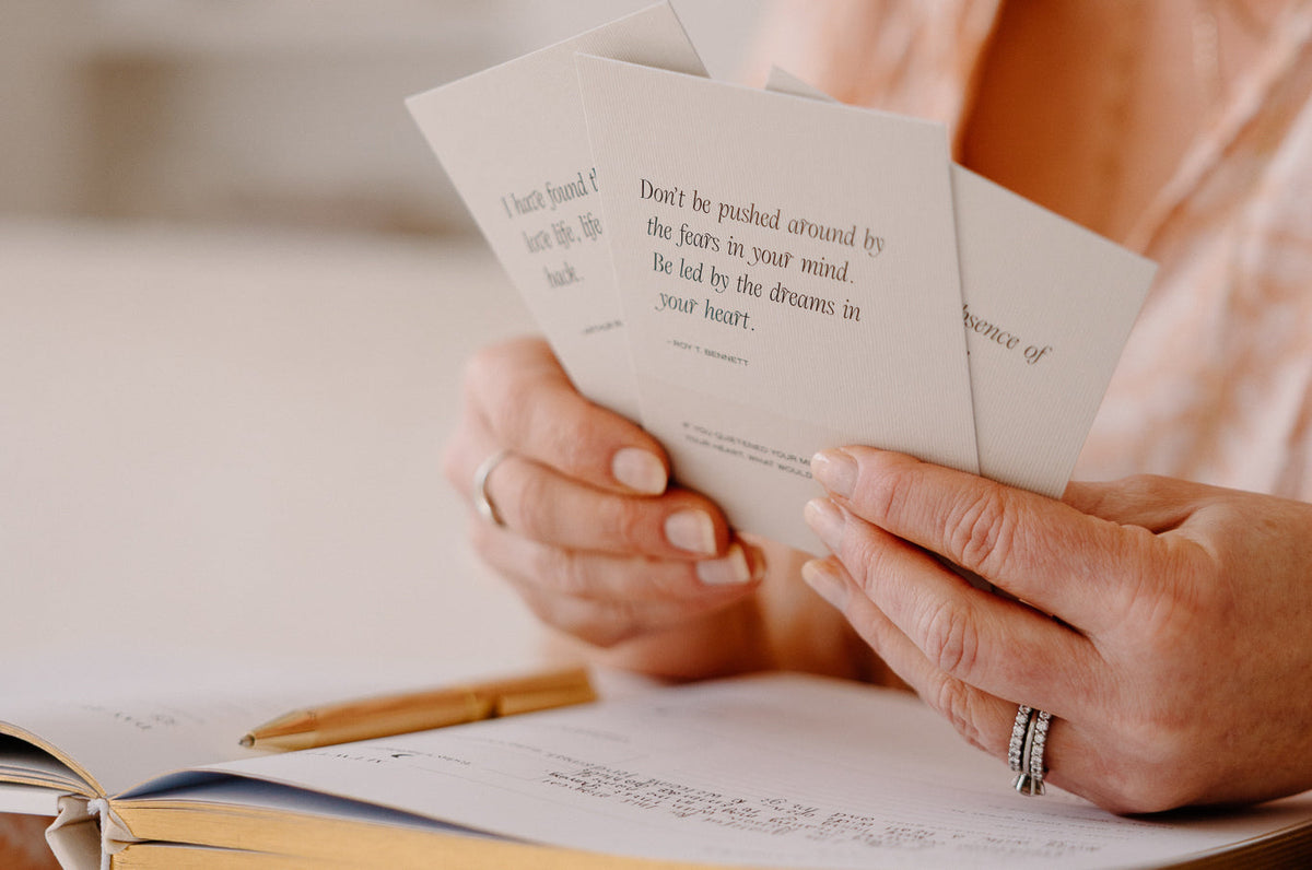 Affirmation cards beside a pen on a pale desk