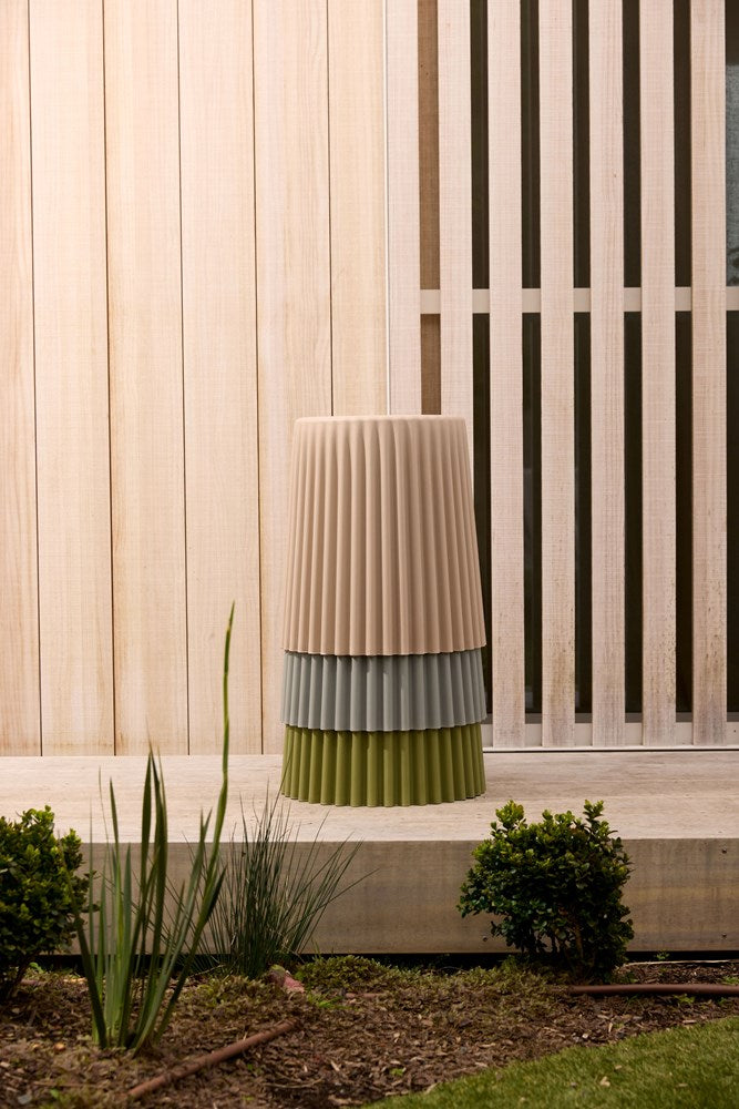 Ribbed stool on paving in front of a slatted timber screen with low planting