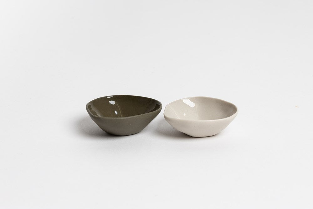Olive green and bone Haan mini dishes side by side, on pale grey