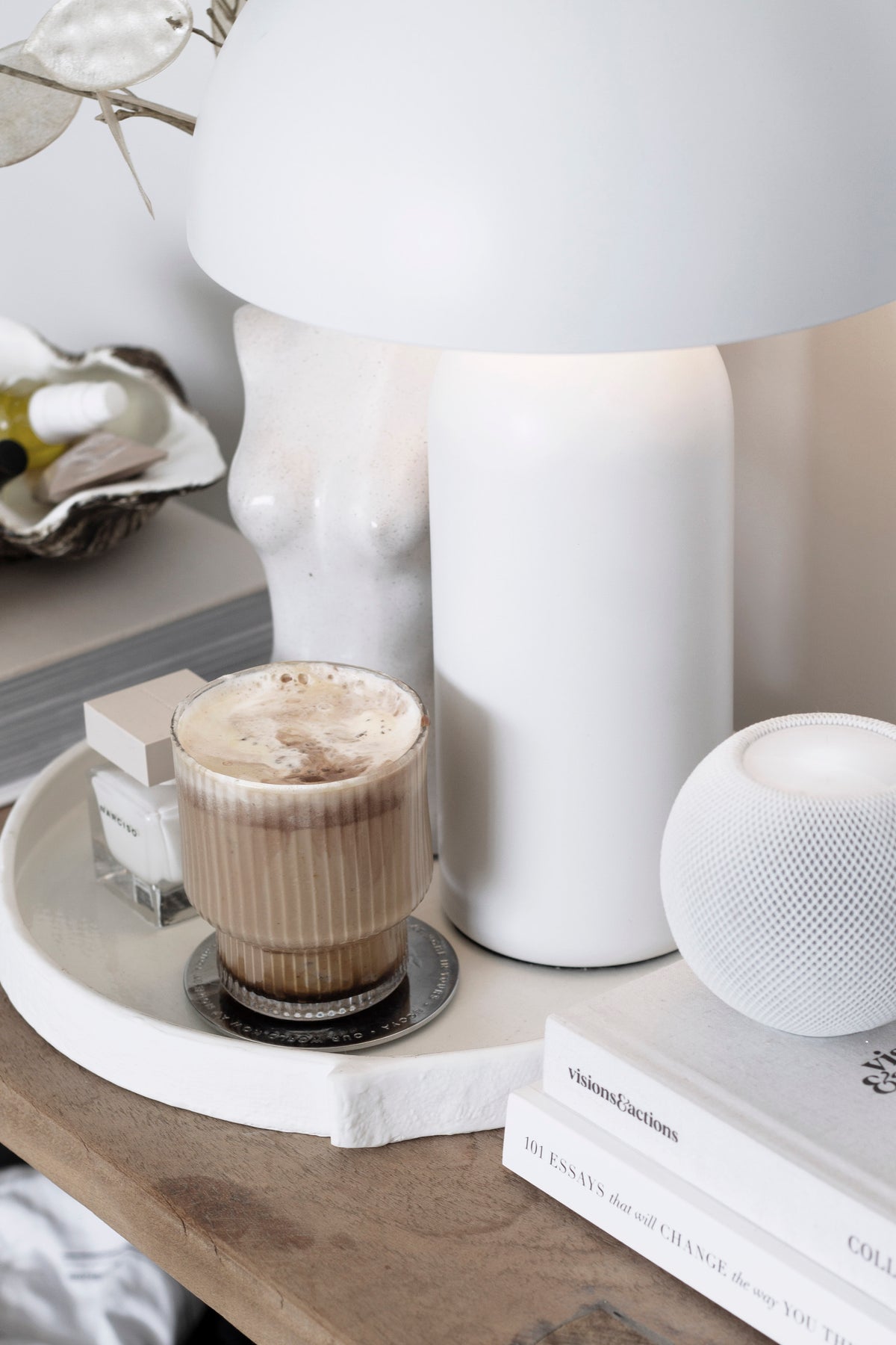 Burlap tray holding a coffee glass and candle beside a white mushroom lamp on a timber table