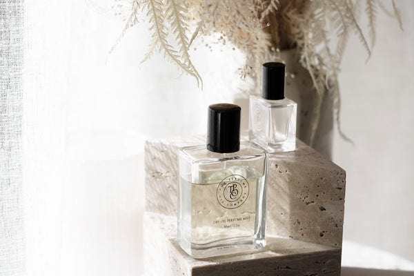 Roll-on perfume oil bottle beside a vase of dried grasses