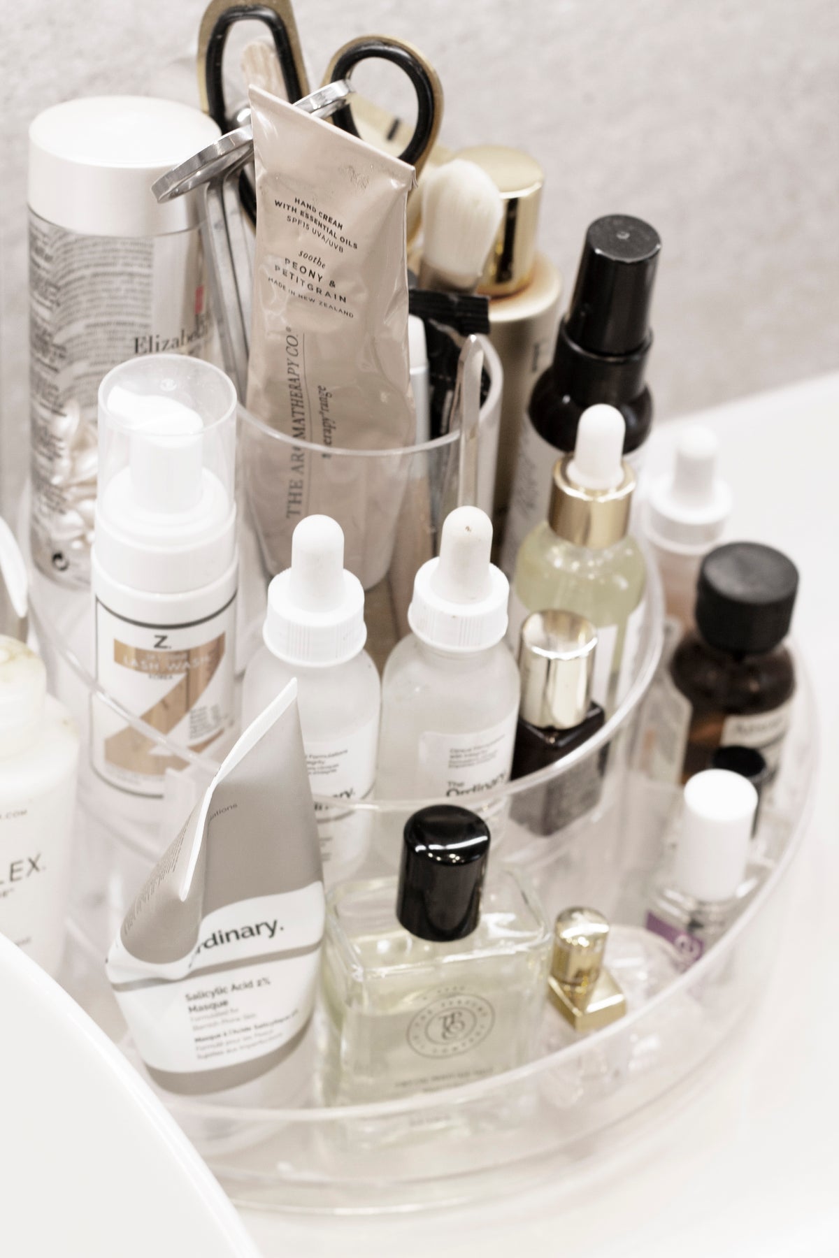 Umbra Cascada clear acrylic organiser filled with serums and cosmetics