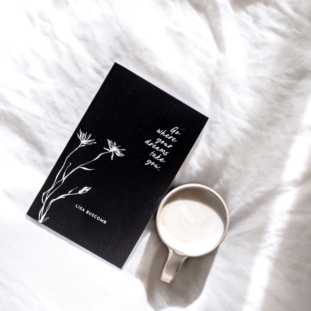 The black gift book on bedding with a white mug