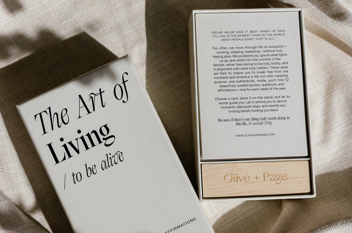 Card deck box beside an open journal on a pale surface