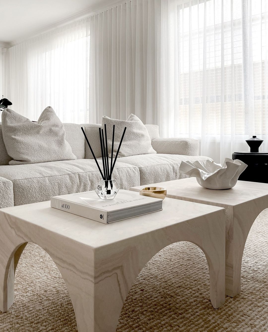 Aroma stick holder with black sticks on a pale arched coffee table in a white living room