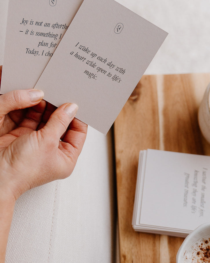 Hand holding an affirmation card above a table