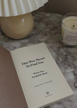 A "This Was Meant To Find You (When You Needed It Most)" book on a table next to a candle. (Brand: Thought Catalog)