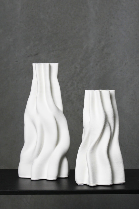 Small and large Anouk white wave vases side by side on a dark shelf