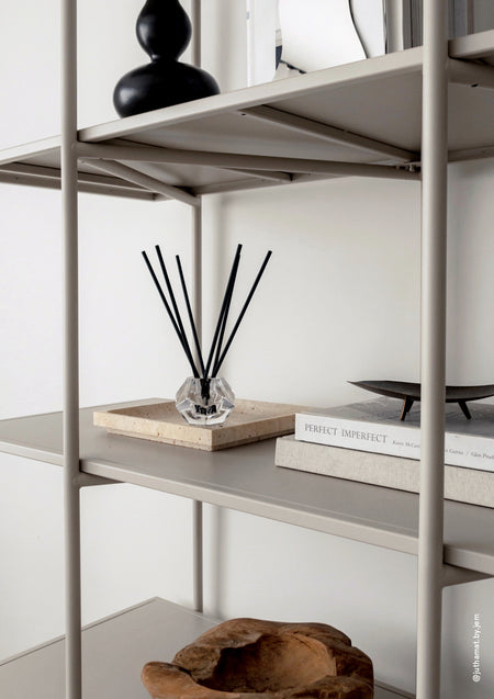 Aroma sticks in a glass holder styled on a shelving unit with books and objects