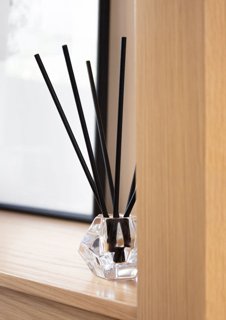 Close view of black aroma stick reeds with a timber wall behind