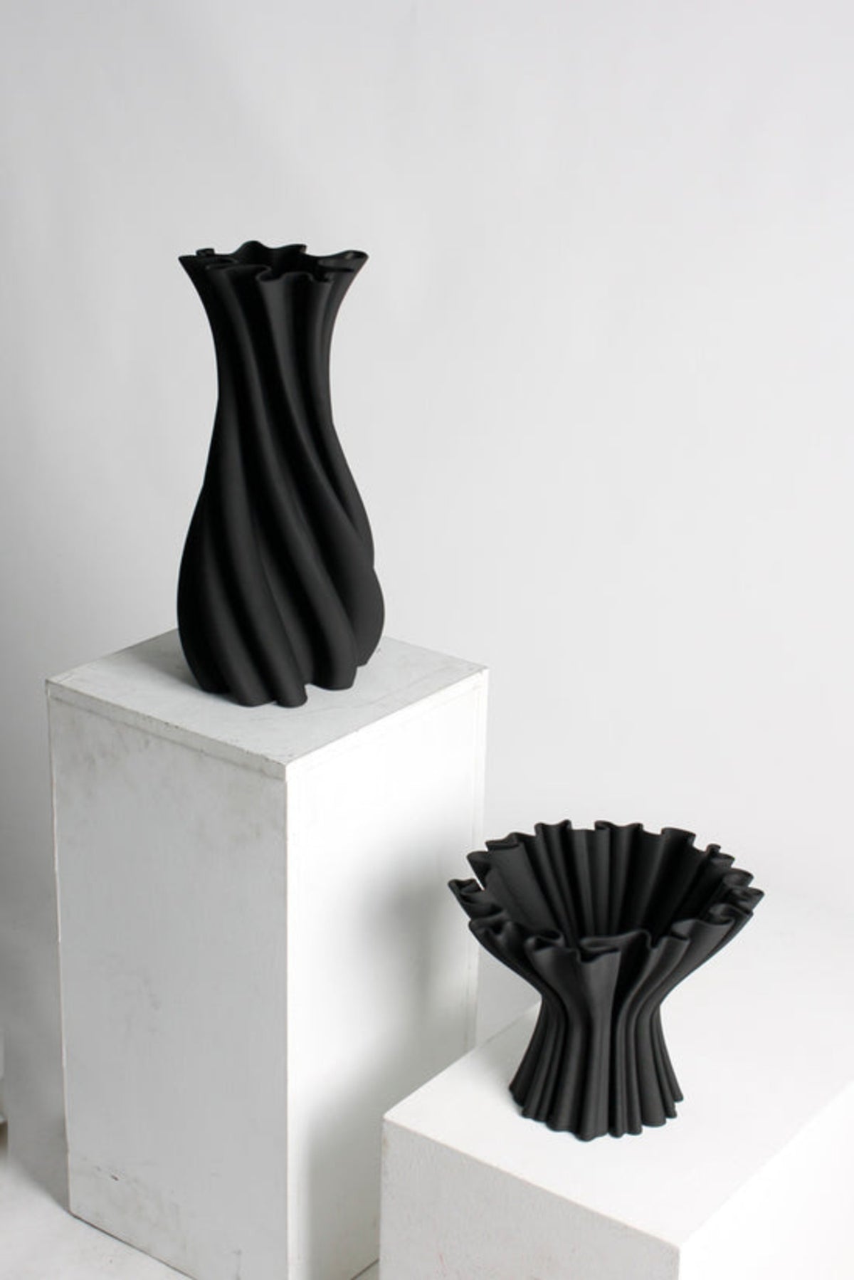 Large and small matte black Camila vases on white plinths