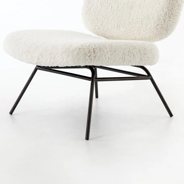 Close view of the chair's black iron legs and cross brace beneath the boucle seat