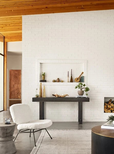 The white boucle chair in a living room beside a black console under a timber ceiling