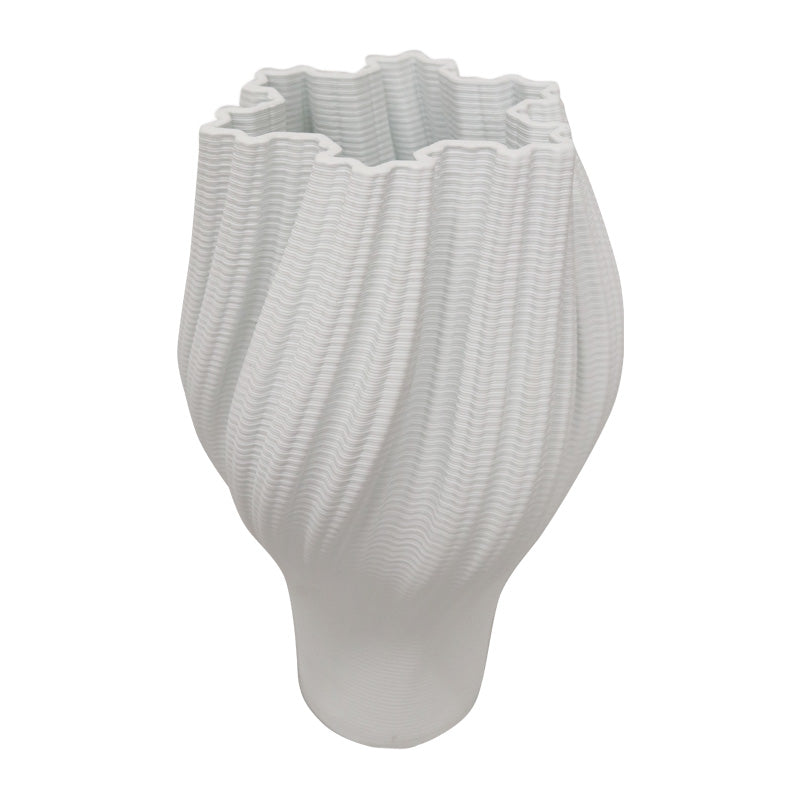 White 3D printed porcelain vase with a rippled ridged form, on a plain background