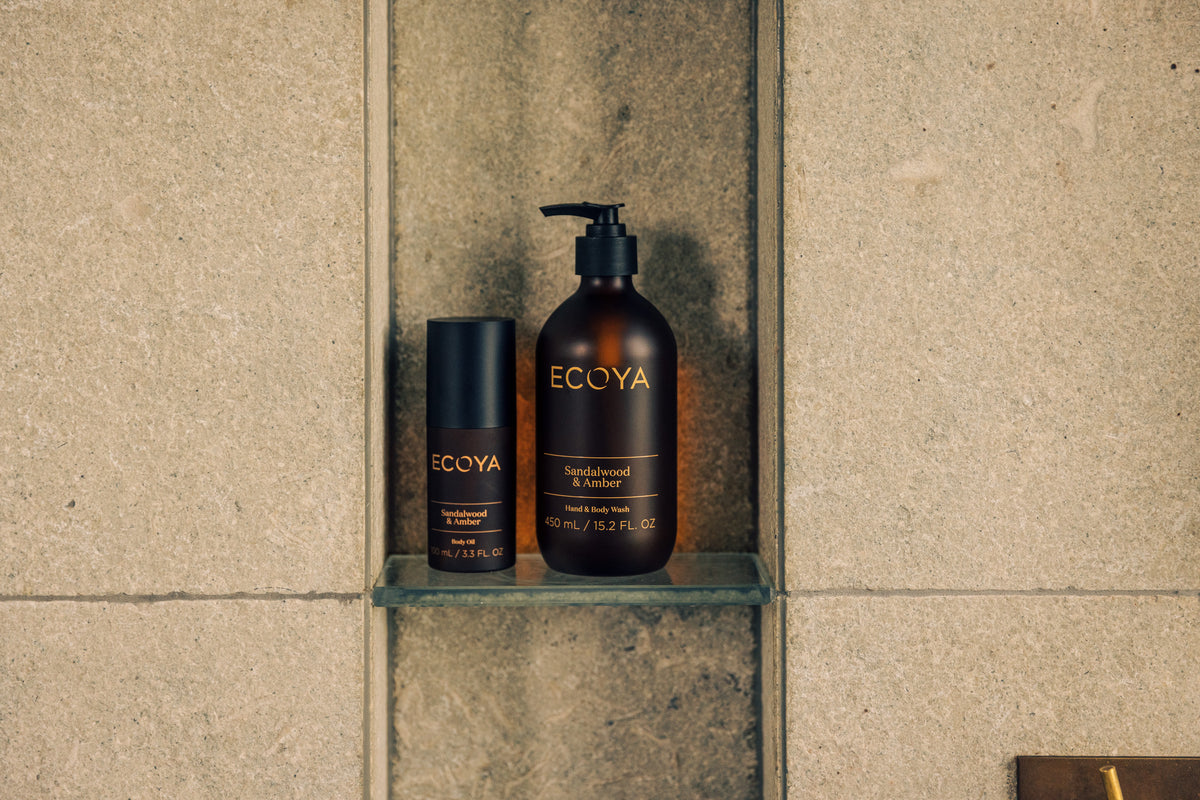 Ecoya Sandalwood & Amber bottles set in a stone shower niche, seen from a distance