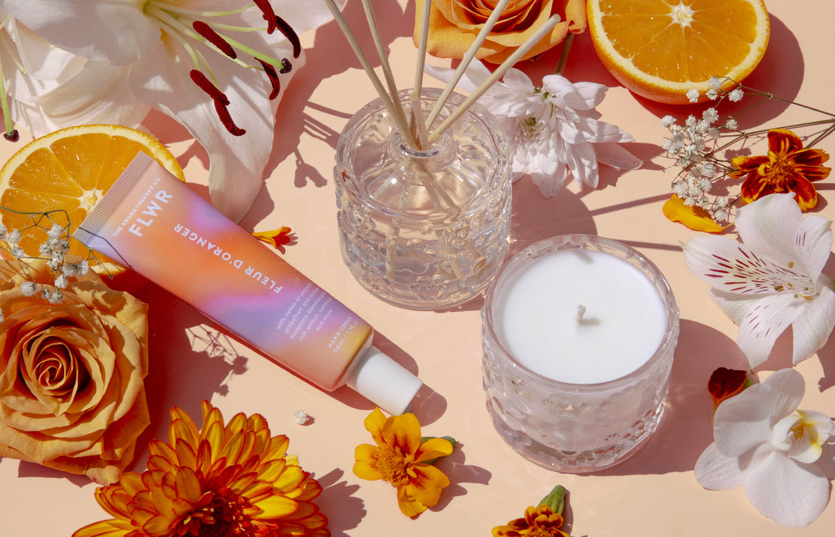 FLWR diffuser, candle and hand cream with orange flowers and citrus slices, landscape view