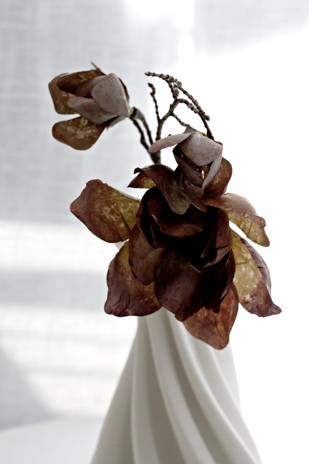Close view of dried magnolia leaves spilling from the white Camila vase