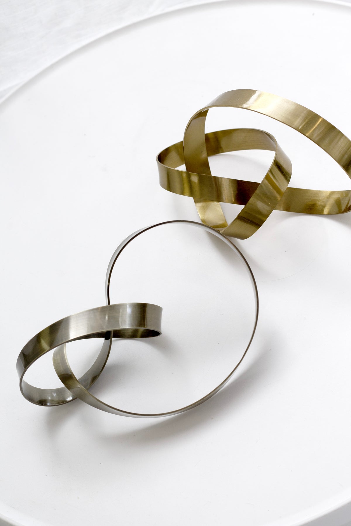 Gold and bronze Infinity Loop sculptures grouped on a round white table