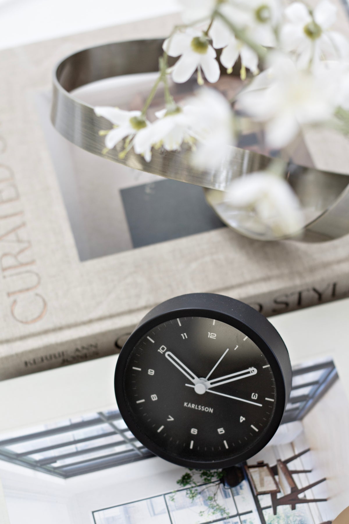 Karlsson Tinge Alarm Clock in black styled on a bedside surface