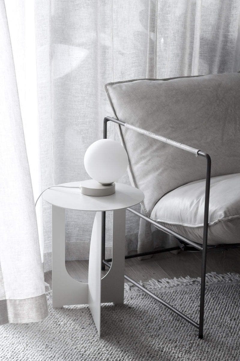A white couch with a Yuri Table lamp from Ned Collections softly glowing next to it.