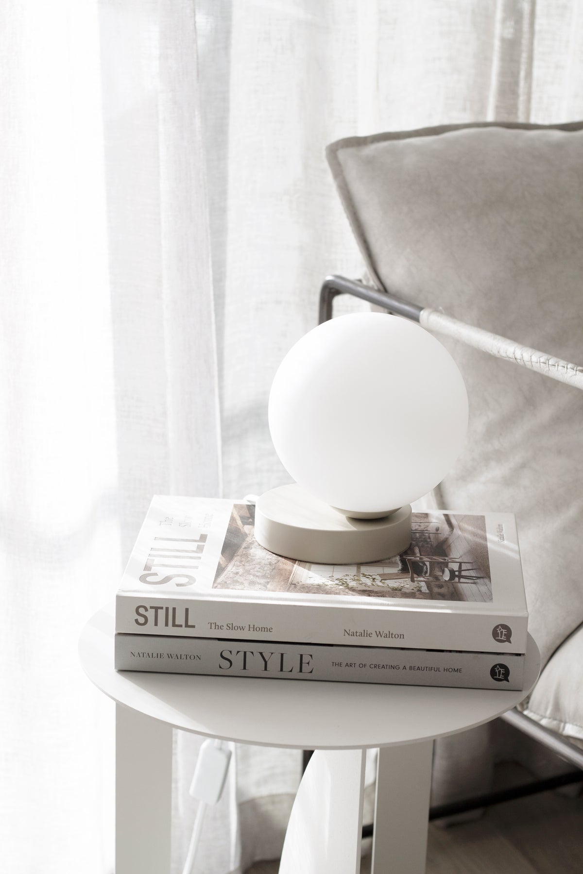 A book placed elegantly on a table illuminated by a Yuri Table lamp with hand blown frosted glass from Ned Collections.