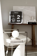 A white Yuri Table lamp with a clock on it is gently illuminated by the soft glow of Ned Collections.