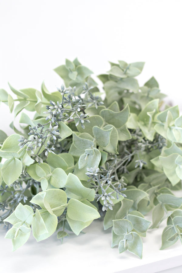 Seeded Eucalyptus Bundle leaves on a white surface showcasing beautiful floral styling. (Product: Seeded Eucalyptus Bundle; Brand: Artificial Flora)