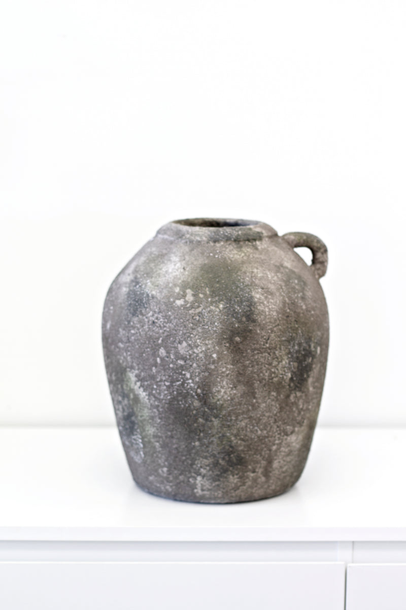 A Flux Home rustic vase with a concrete look sits on a white table.