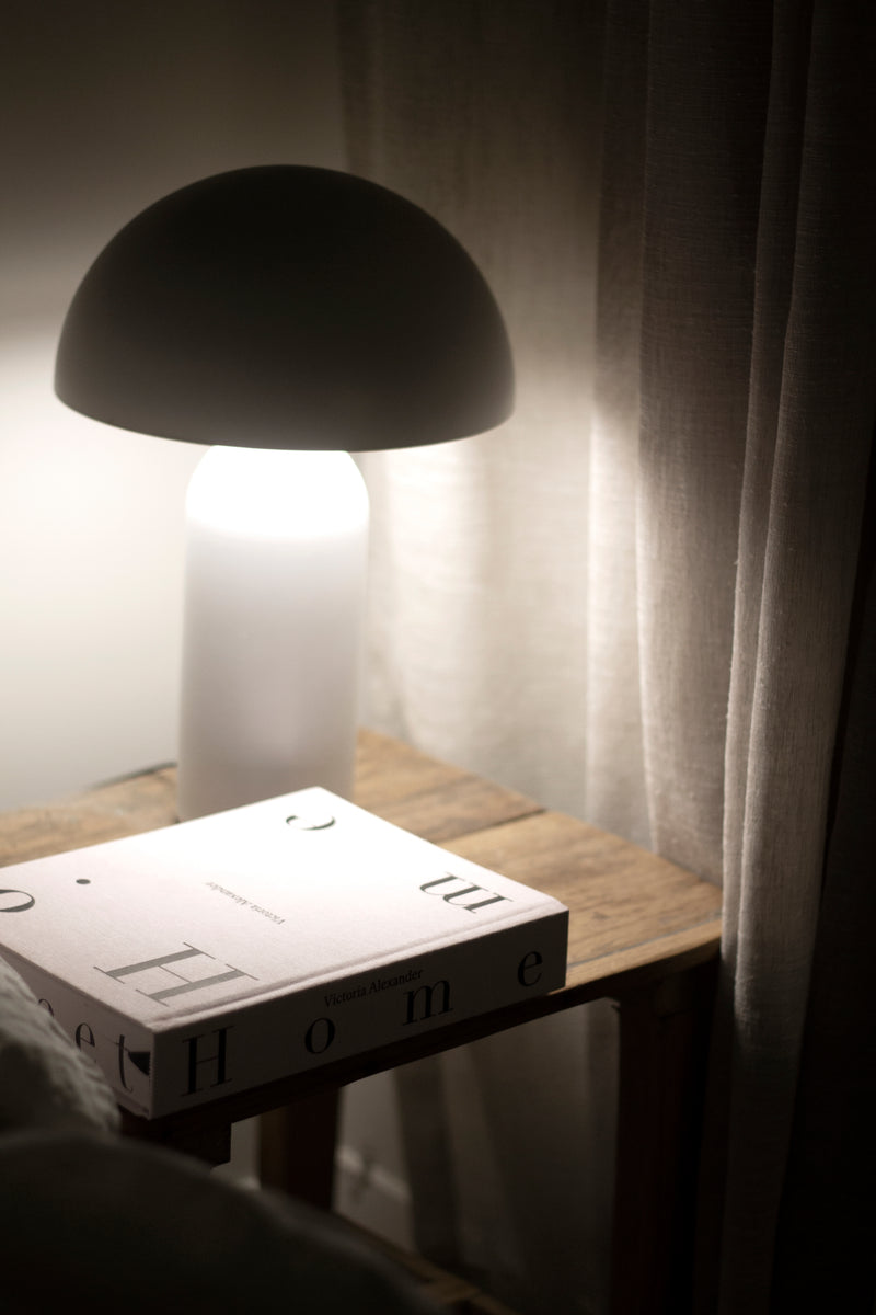 A Victoria Alexander book is sitting on a table next to a lamp in a Home.