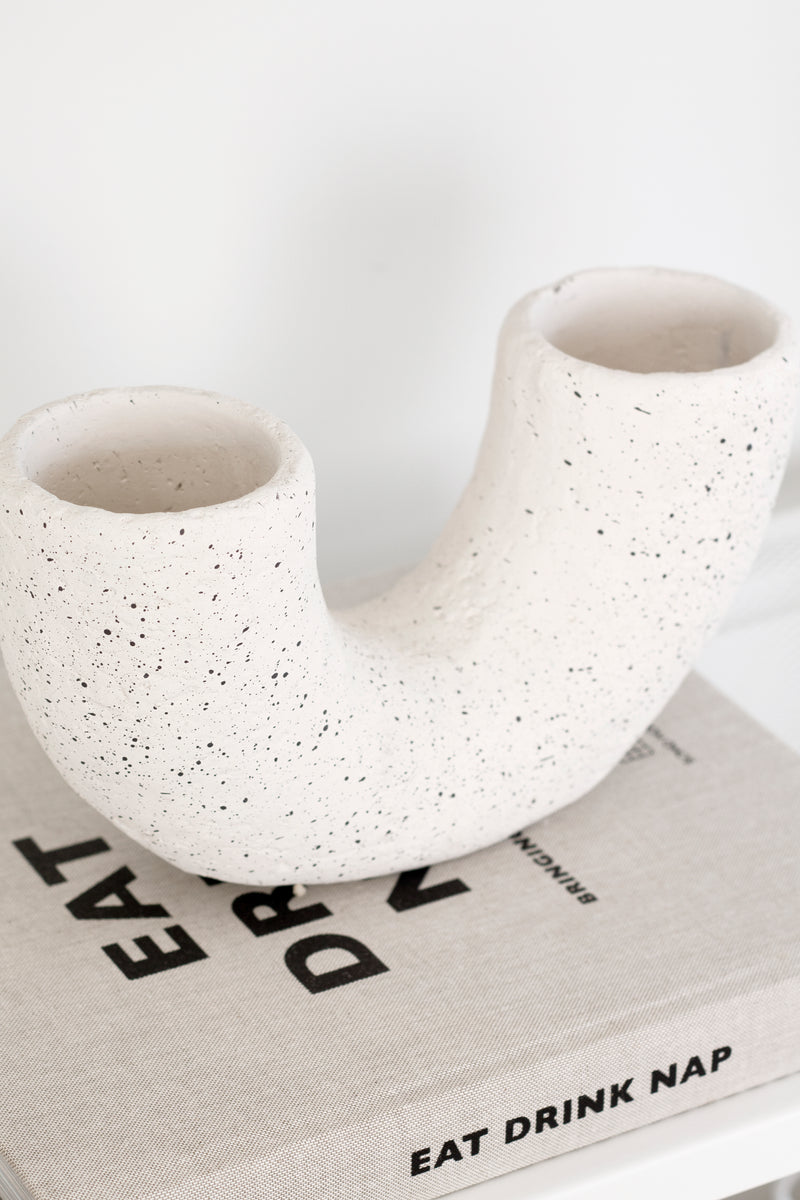 The Vases Mia Off-White Pipe Vase, made of cement material, sits on top of a book.