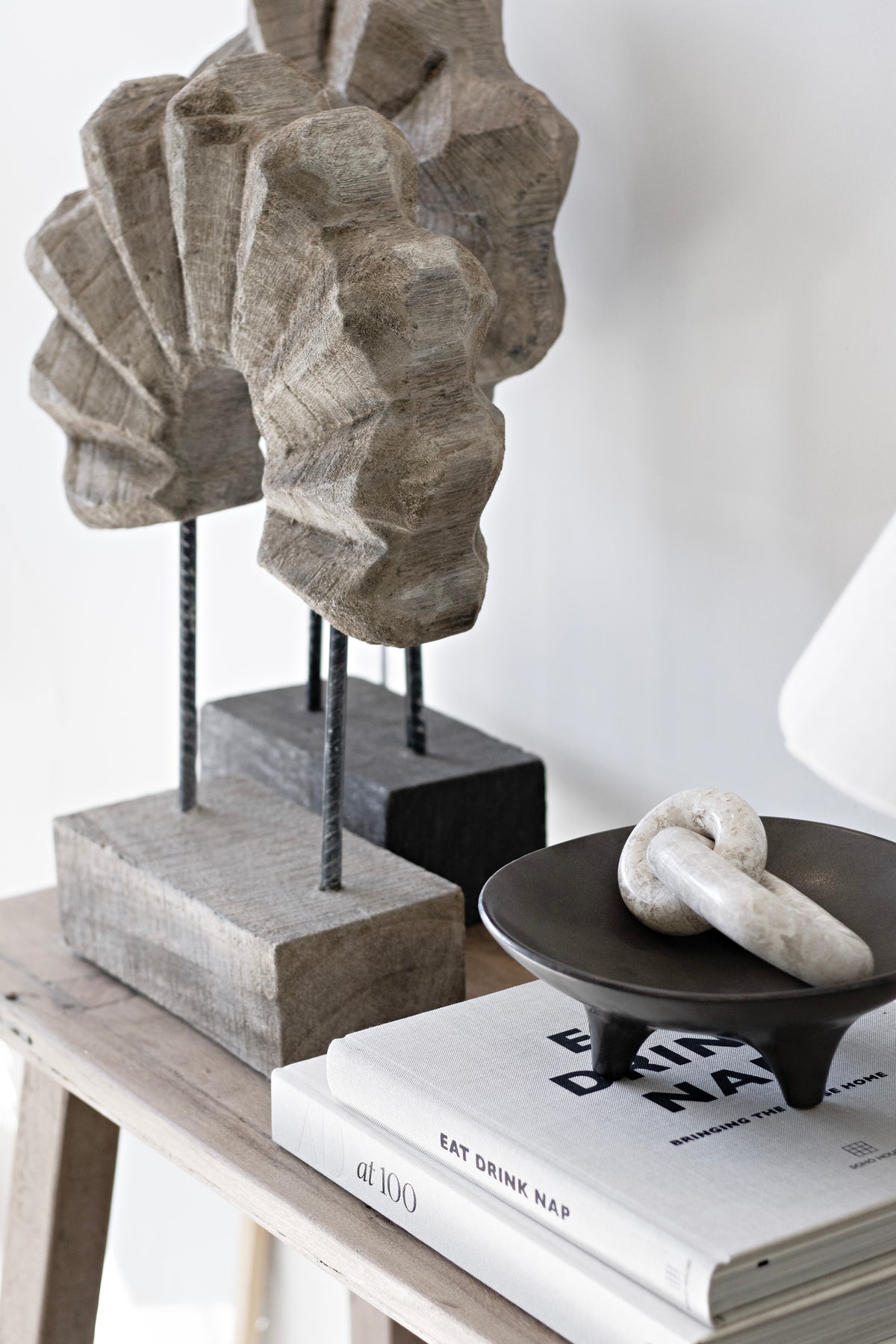 Timber arch sculpture on a console with stacked books and a knot ornament in a black dish