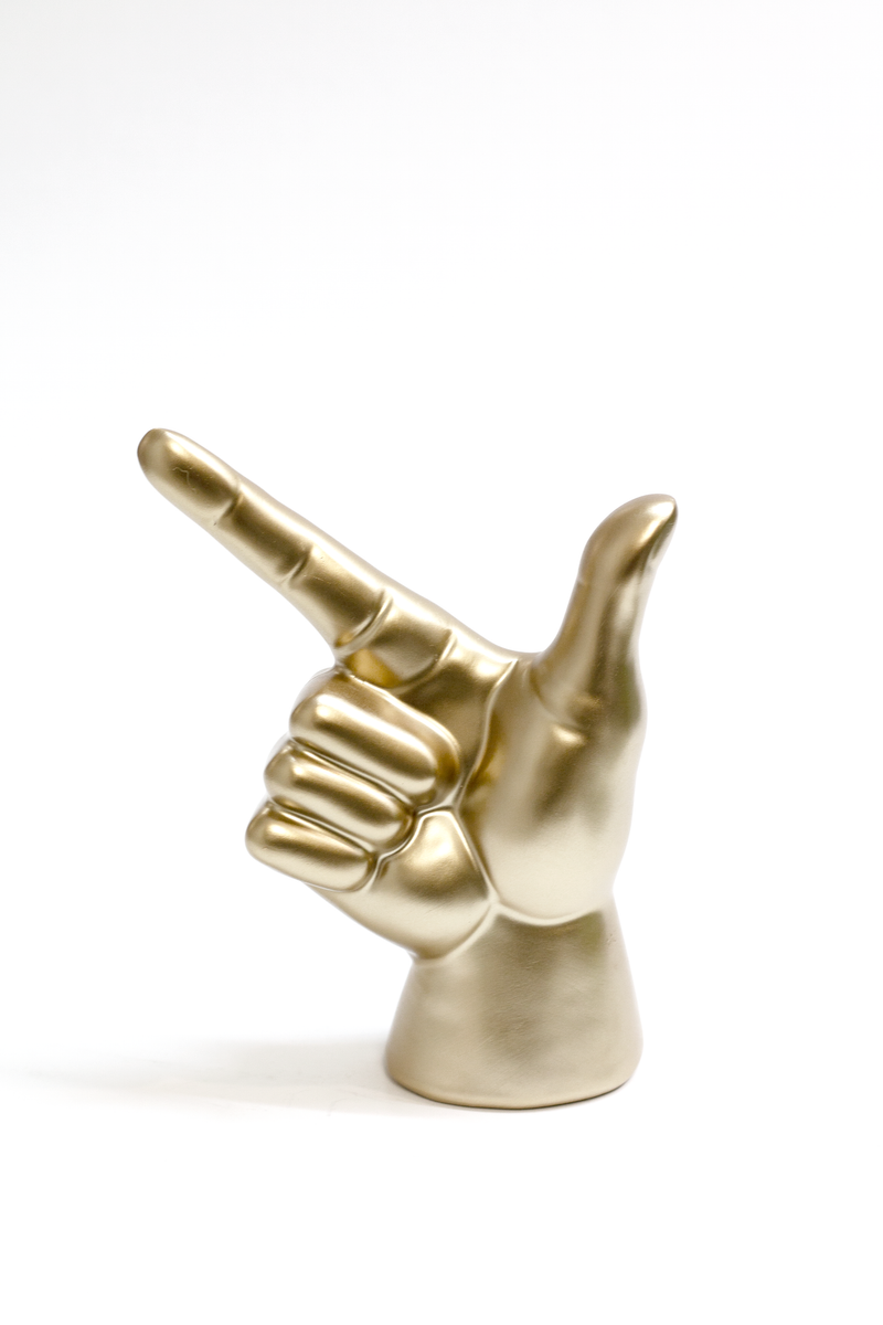 A brass-coloured Flux Home Lucky Hand statue, featuring a pointing finger as the focal point.