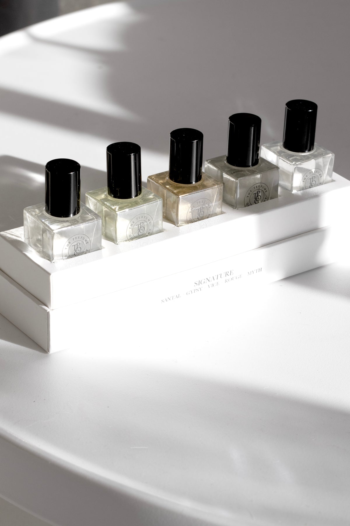 Five roll-on perfume oil bottles in a row on a white ledge