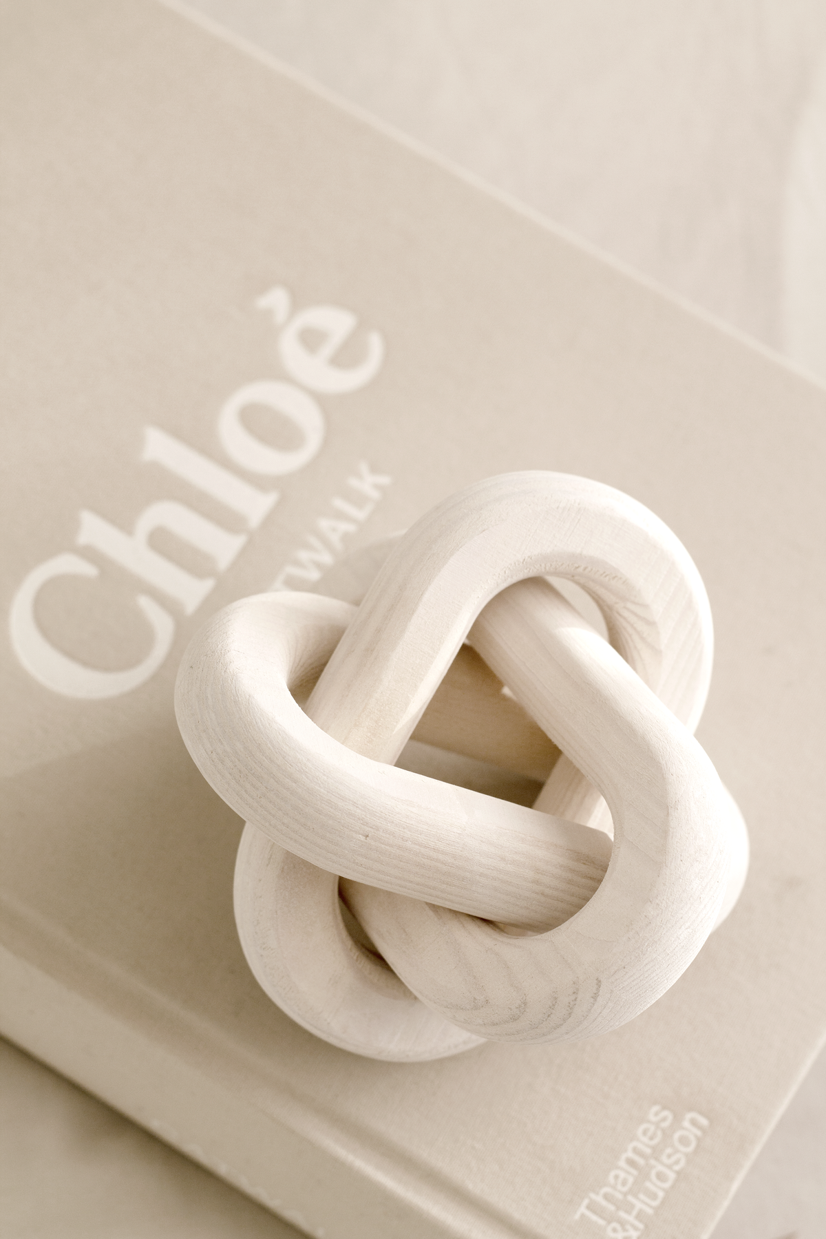 Cream knot ornament resting on a large format fashion book