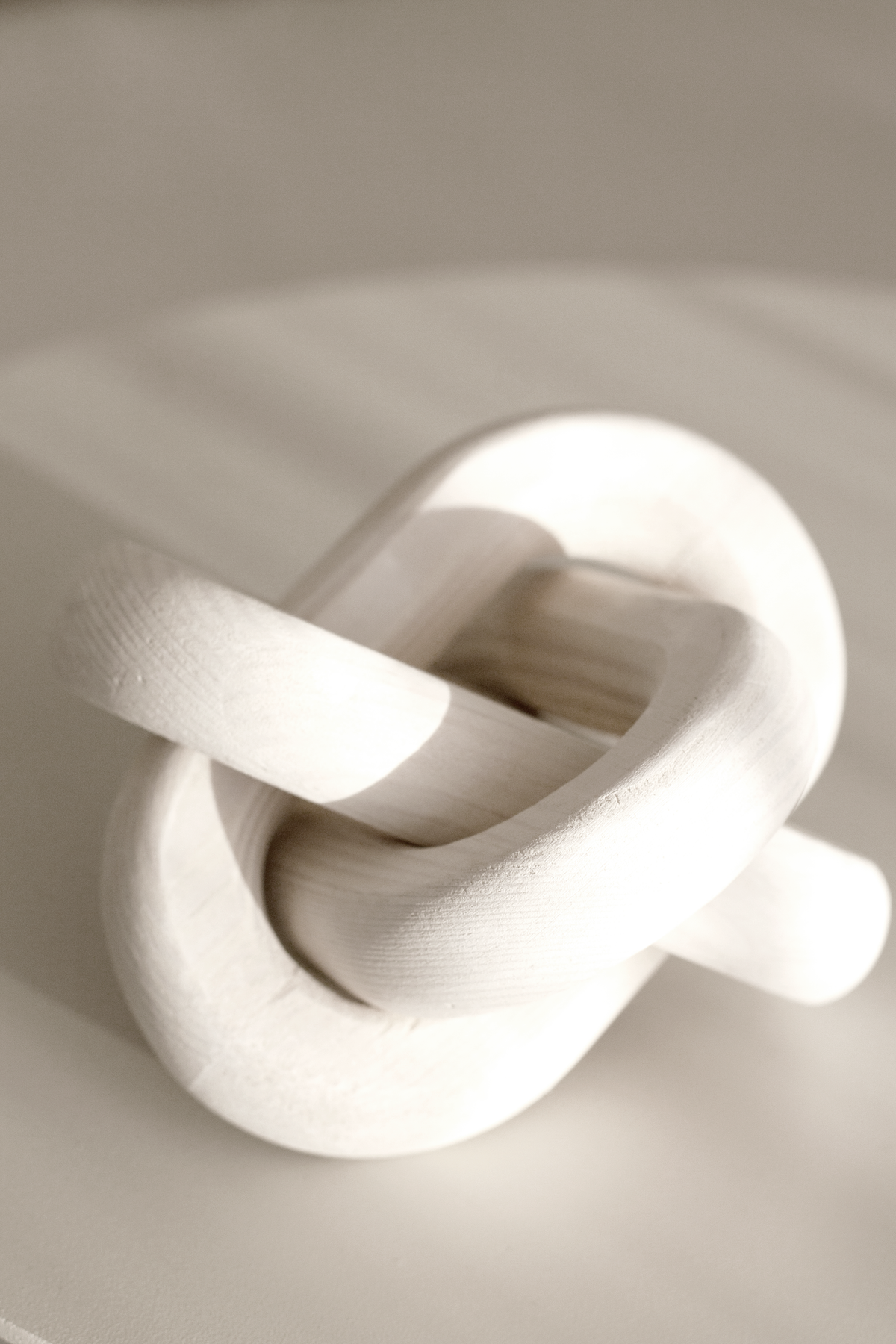 White knot ornament on a pale surface, side light picking out the curves