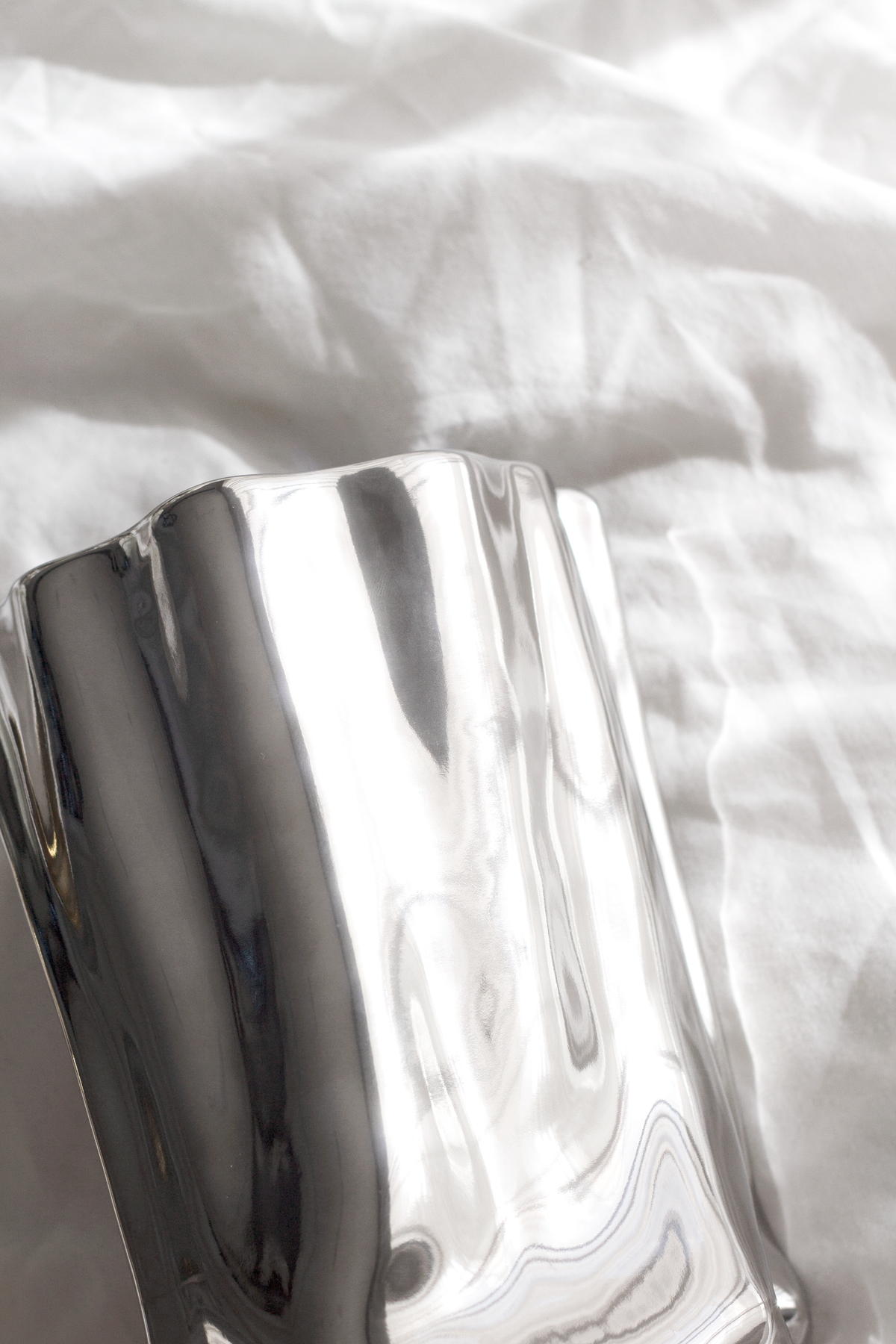 Close view of the silver metallic bag vase on crumpled white linen
