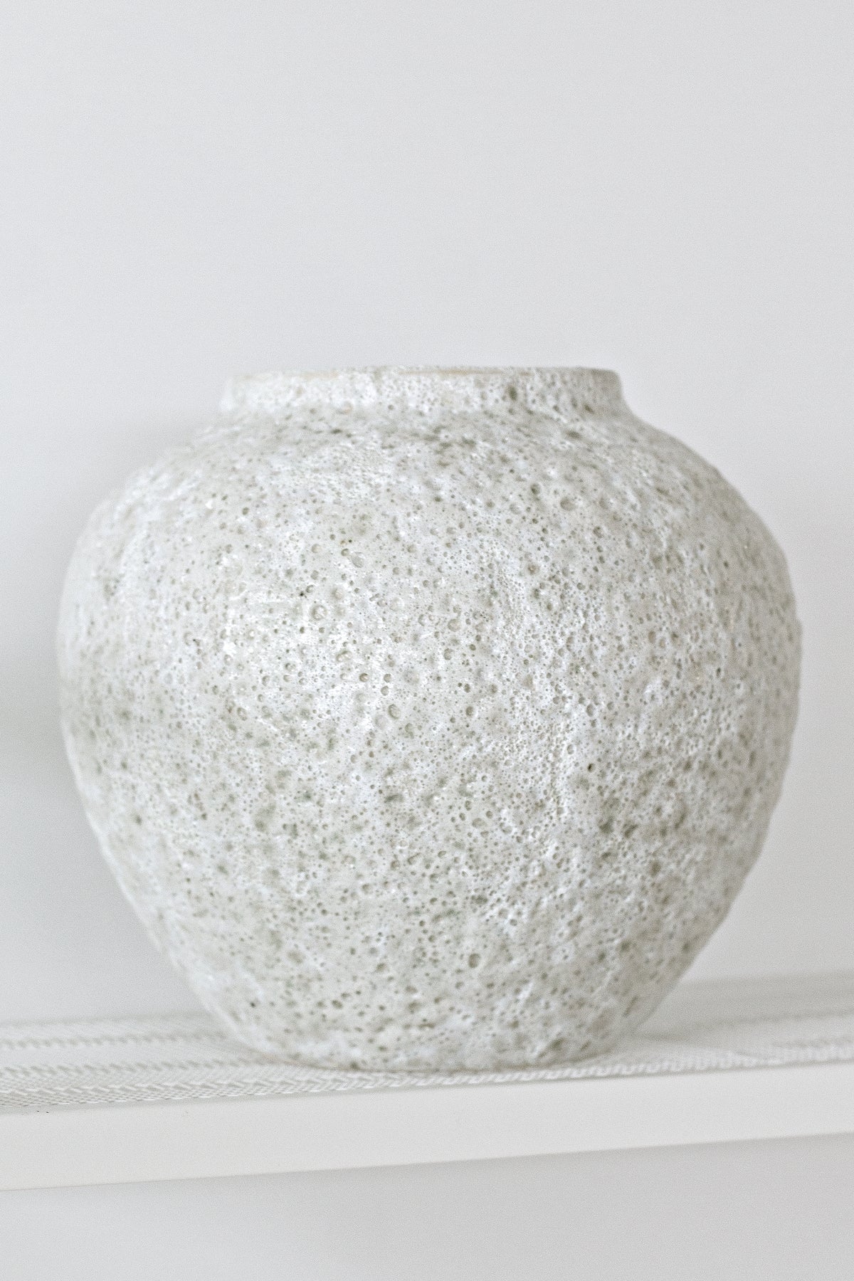 Short Seafoam vase empty on a white shelf, turned to show the rounded shoulder and rim