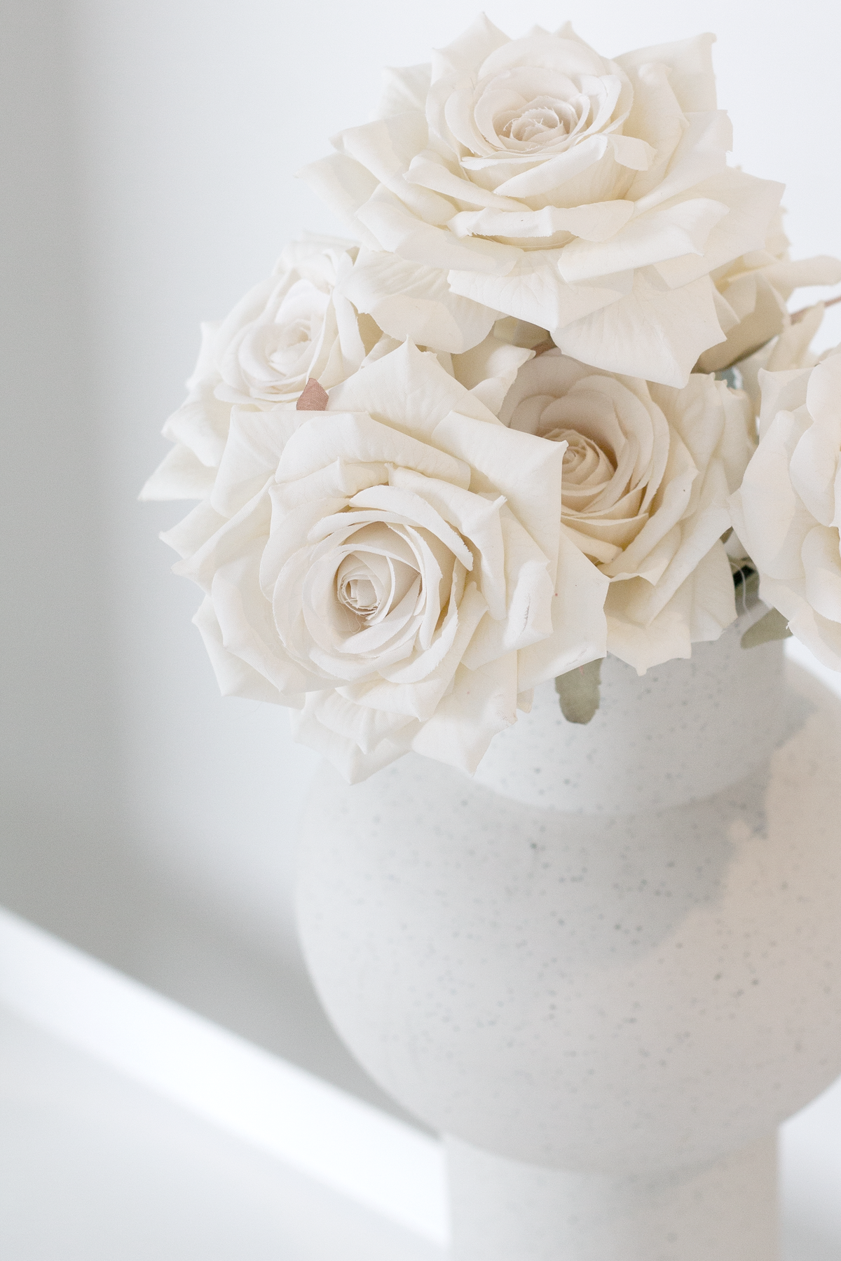 Close view of champagne roses in a white bulb vase