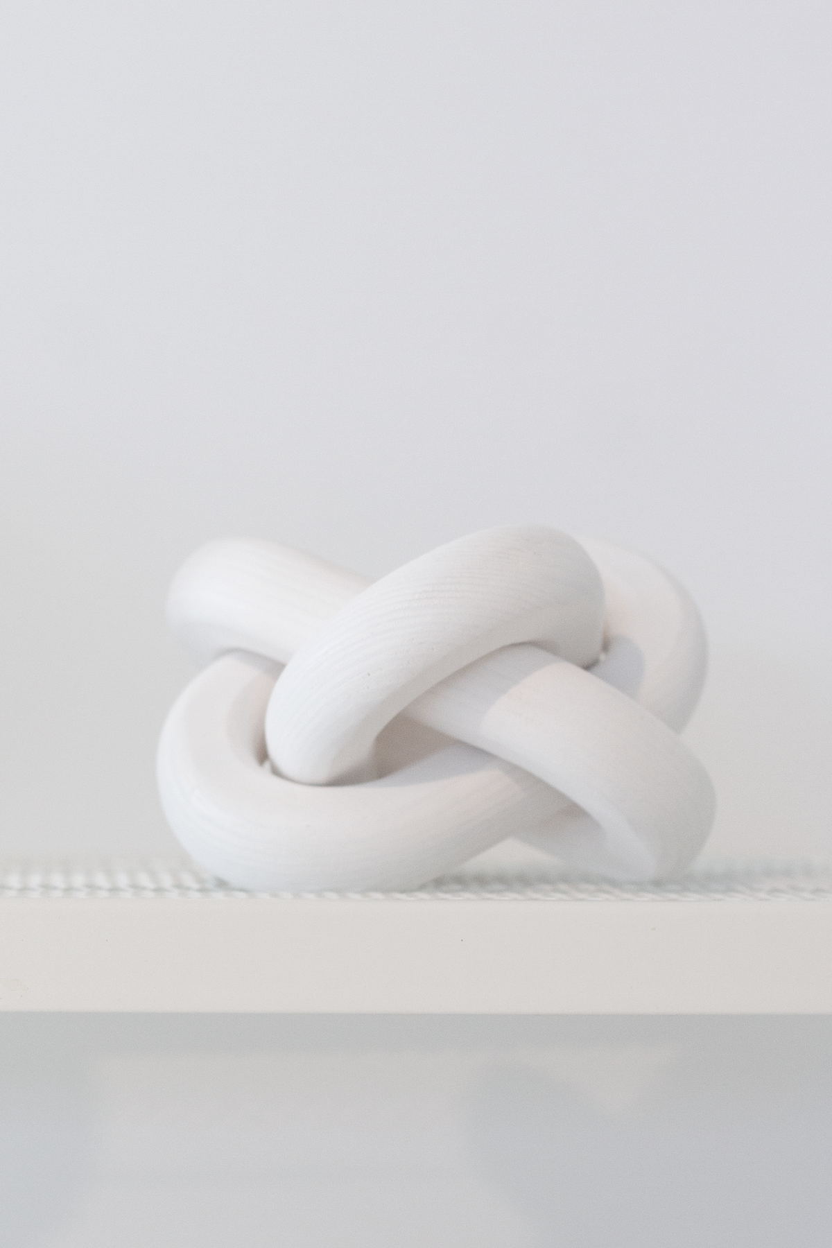 White knot ornament on a white ledge against a plain wall