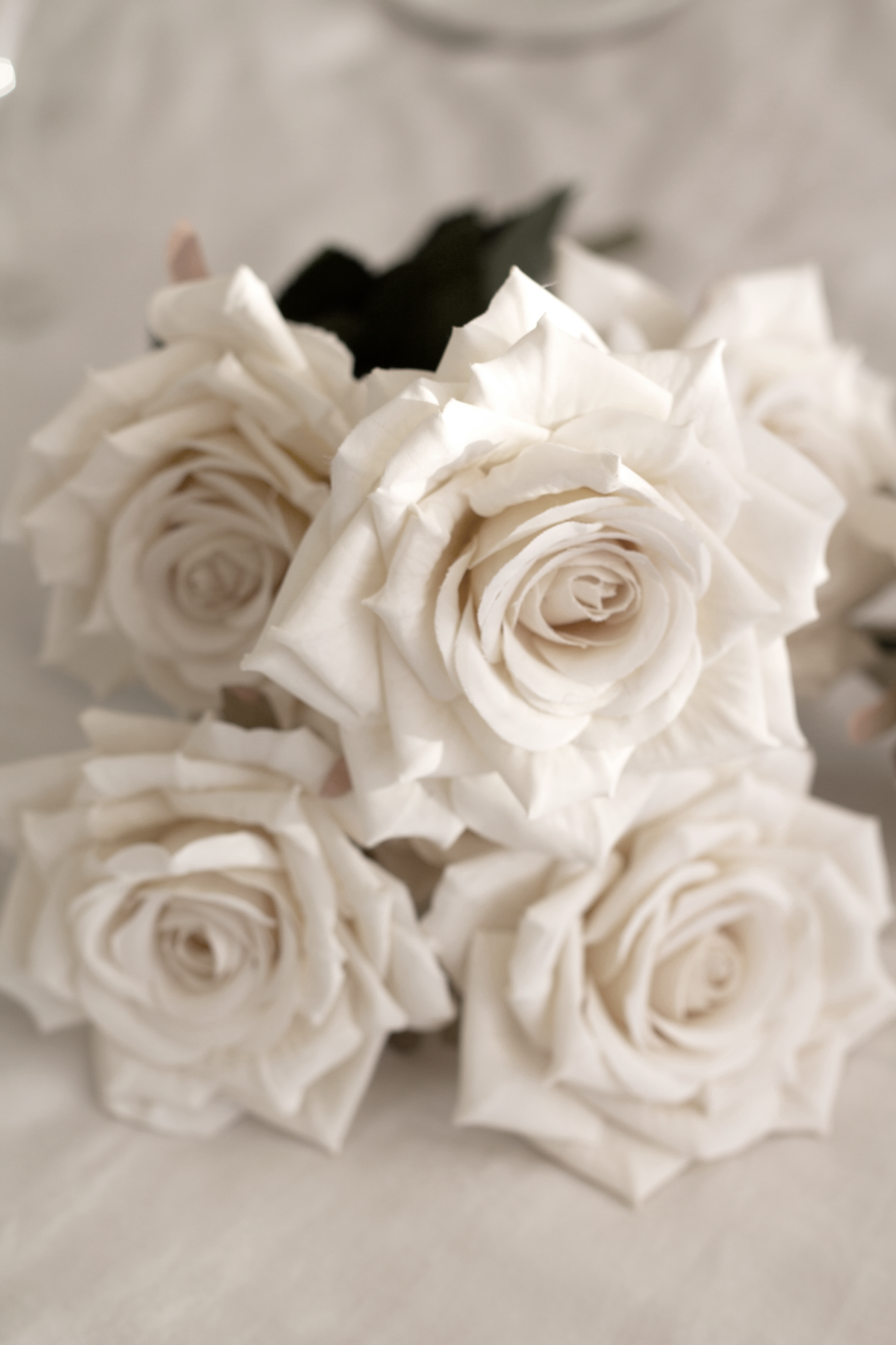 Champagne faux rose bouquet lying on cream linen