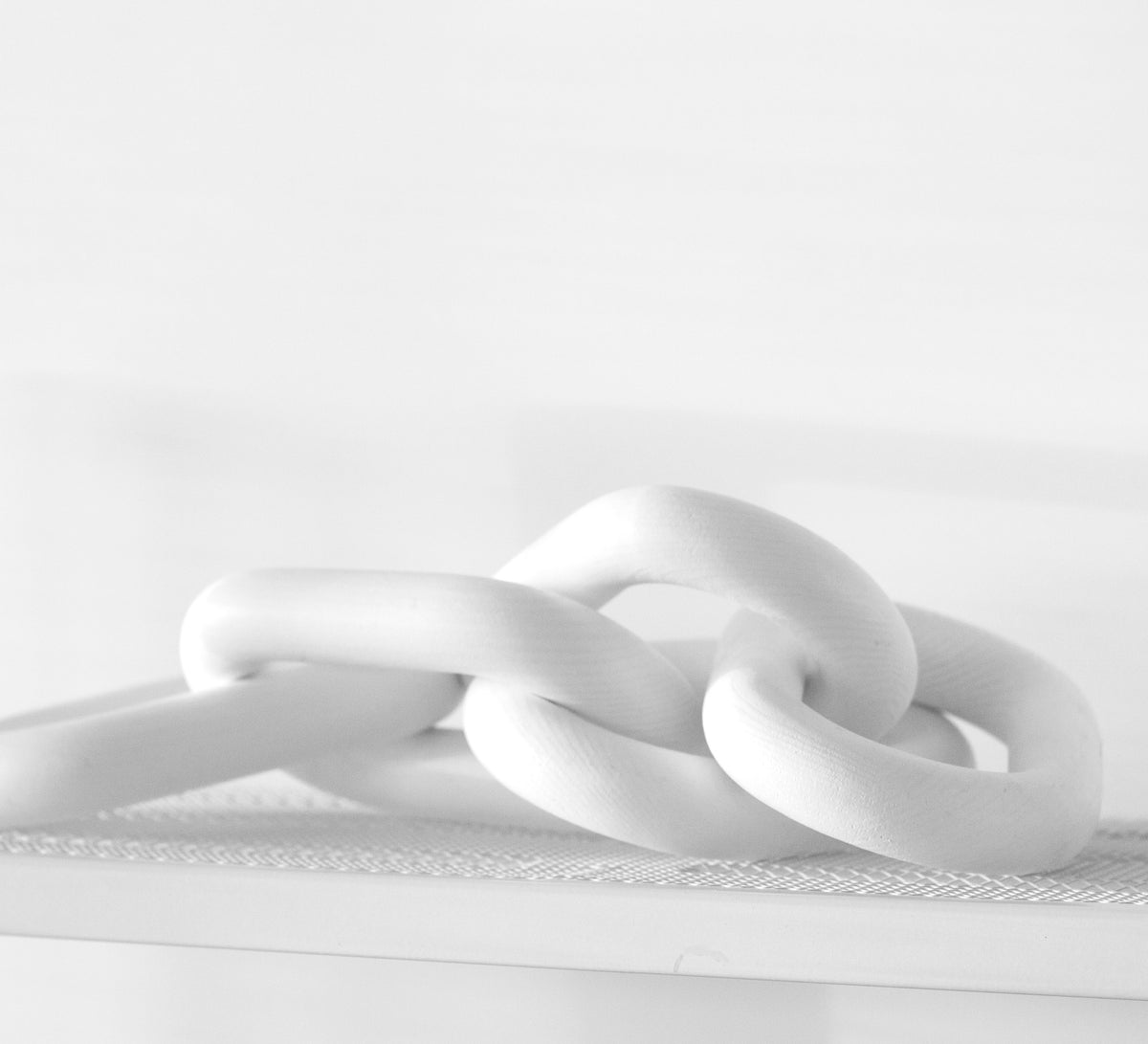 Close view of the white wooden chain links resting on a pale shelf