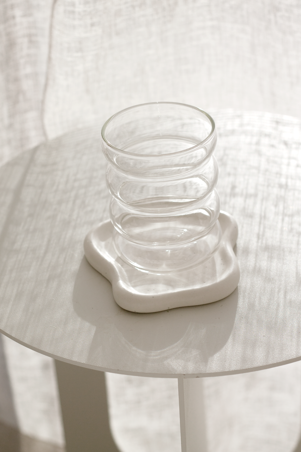 White cloud trinket dish used as a coaster under a ribbed glass tumbler